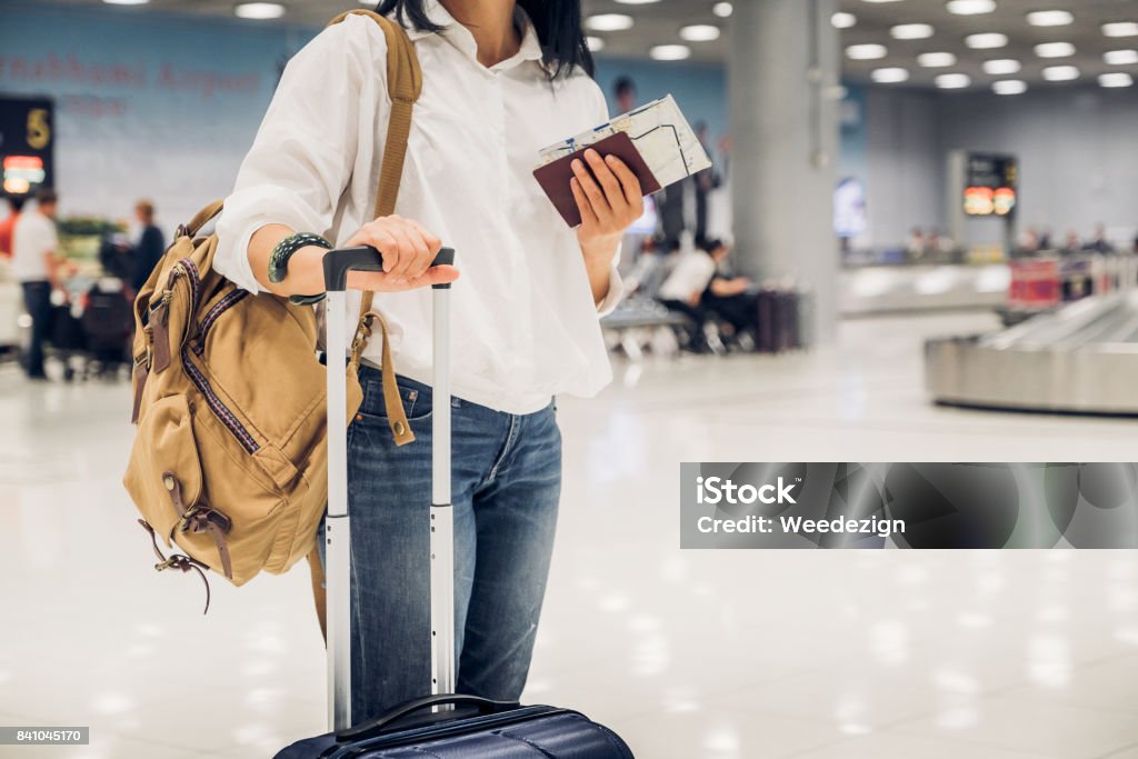 Mujer backpacker celebración pasaporte y mapa con maleta en comprobar el equipaje a facturar en concepto de viajero terminal, Aeropuerto - Foto de stock de Emigración e inmigración libre de derechos