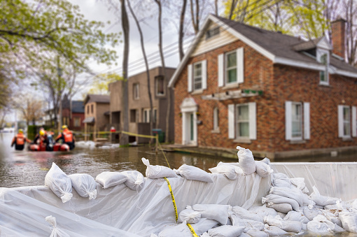 Flood Protection Sandbags with flooded homes in the background (Montage)