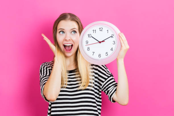 istock Young woman holding a clock 841050698