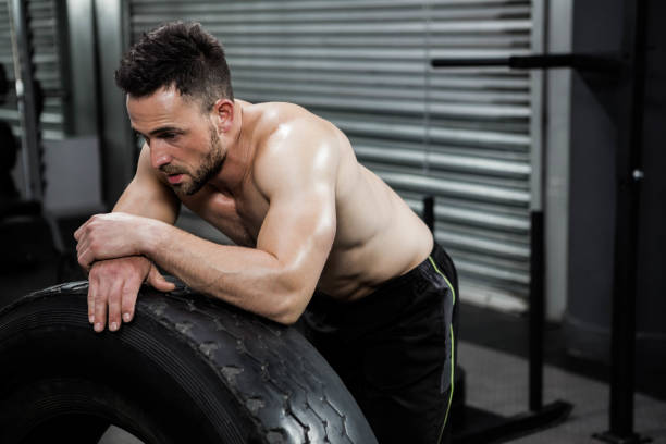 istock Tired shirtless man leaning against heavy tire 841051166