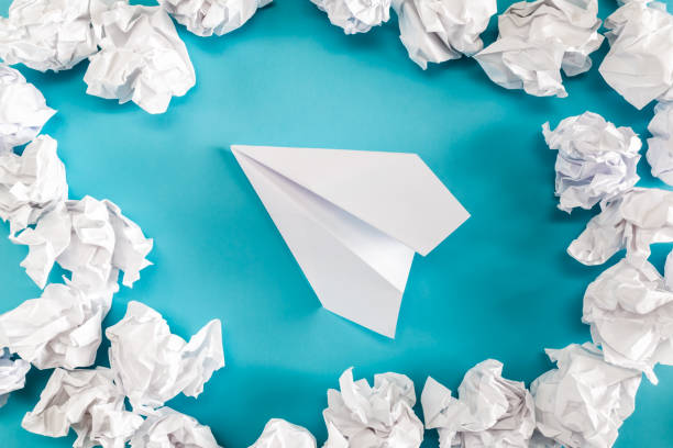 Paper airplane with crumpled failed paper balls