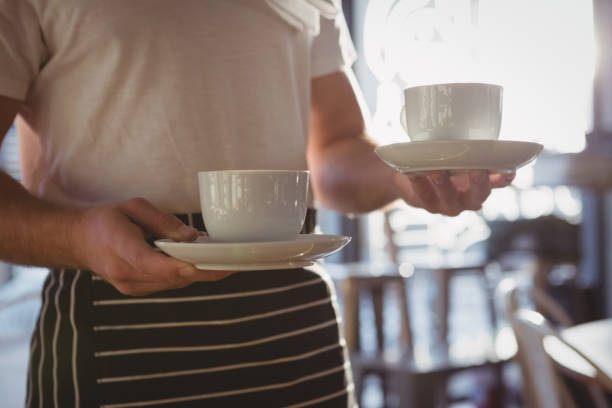 istock Mid section of waiter holding coffee cups in cafe 841054582