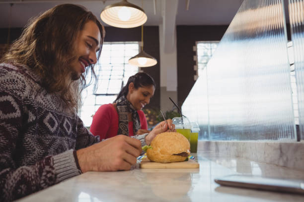 istock Man with friend having burger in cafe 841056722
