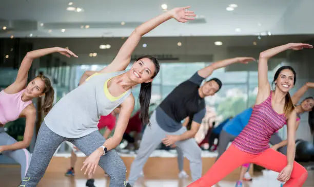 Group of people in an aerobics class at the gym stretching looking very happy â fitness concepts