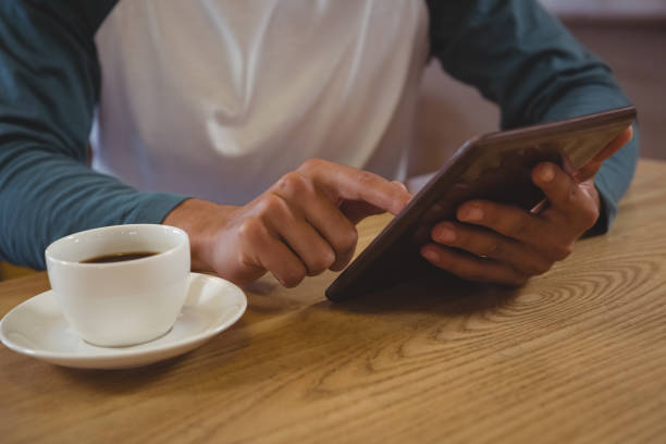 istock Mid section of man with coffee using tablet in cafe 841069878