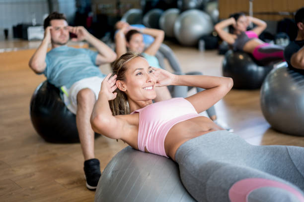 People at the gym in an exercise class using fitness balls Happy group of people at the gym in an exercise class using fitness balls â healthy lifestyle concepts fitness ball photos stock pictures, royalty-free photos & images