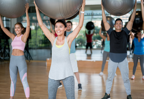 Group of Latin American people exercising at the gym using fitness balls - healthy lifestyle concepts