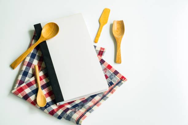 istock recipe book with Wooden spoons isolated on white background 841075520
