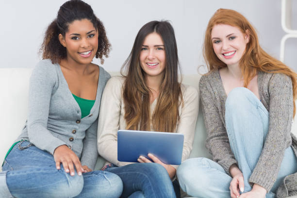 istock Female friends using digital tablet together on sofa 841086420