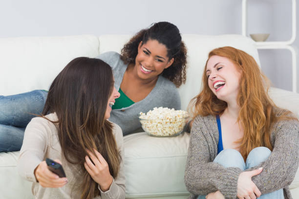 istock Cheerful friends with remote control and popcorn bowl at home 841086586