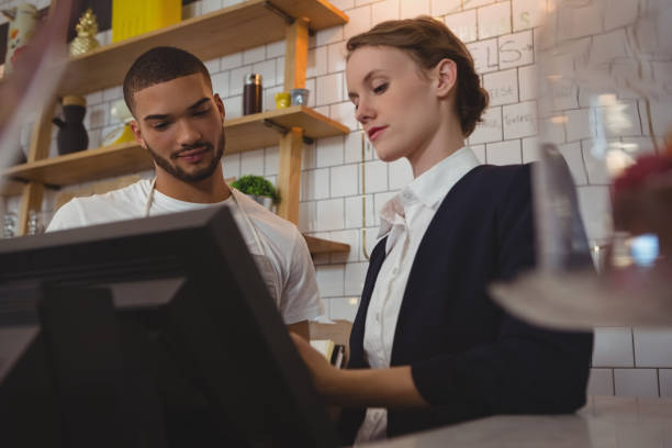 istock Female owner with waiter using cash register in cafe 841091276