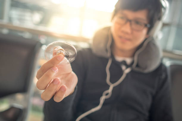 istock Young asian man playing spinner fidget while waiting in airport terminal 841095264