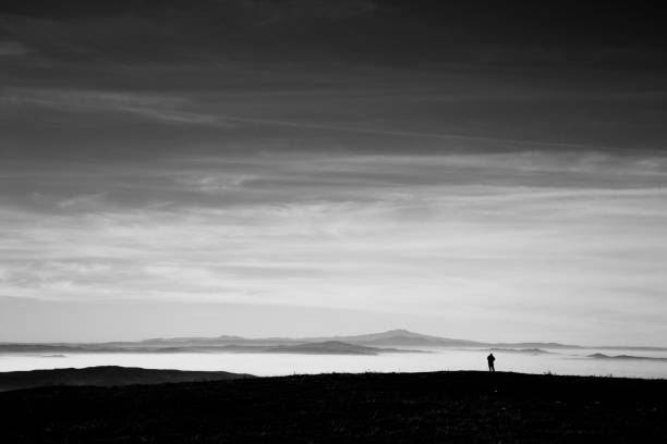 istock A man in a mountains scenery, looking at a valley filled by fog and beneath a big, deep sky 841099256