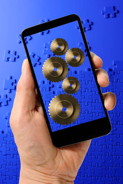 istock Holding a smart phone with gears against blue jigsaw puzzle 841106888