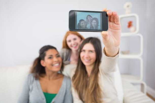 istock Friends photographing themselves with smartphone on sofa 841110508