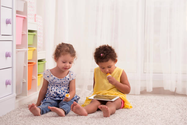 istock Little girls eating popsicle / flavored ice, watching tablet computer. 841129826