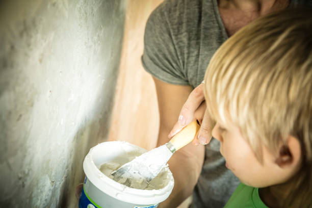 padre e figlio con cazzuola che intonacano un muro - plaster plasterer work tool child foto e immagini stock