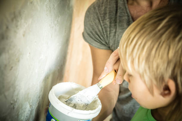 father and son with trowel plastering a wall - plaster plasterer work tool child imagens e fotografias de stock