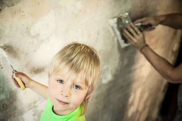 padre e figlio con cazzuola che intonacano un muro - plaster plasterer work tool child foto e immagini stock