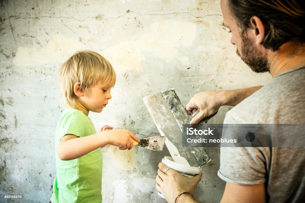 Father and son with trowel plastering a wall Father Stock Photo