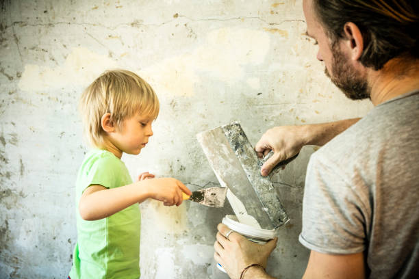 father and son with trowel plastering a wall - plaster plasterer work tool child imagens e fotografias de stock