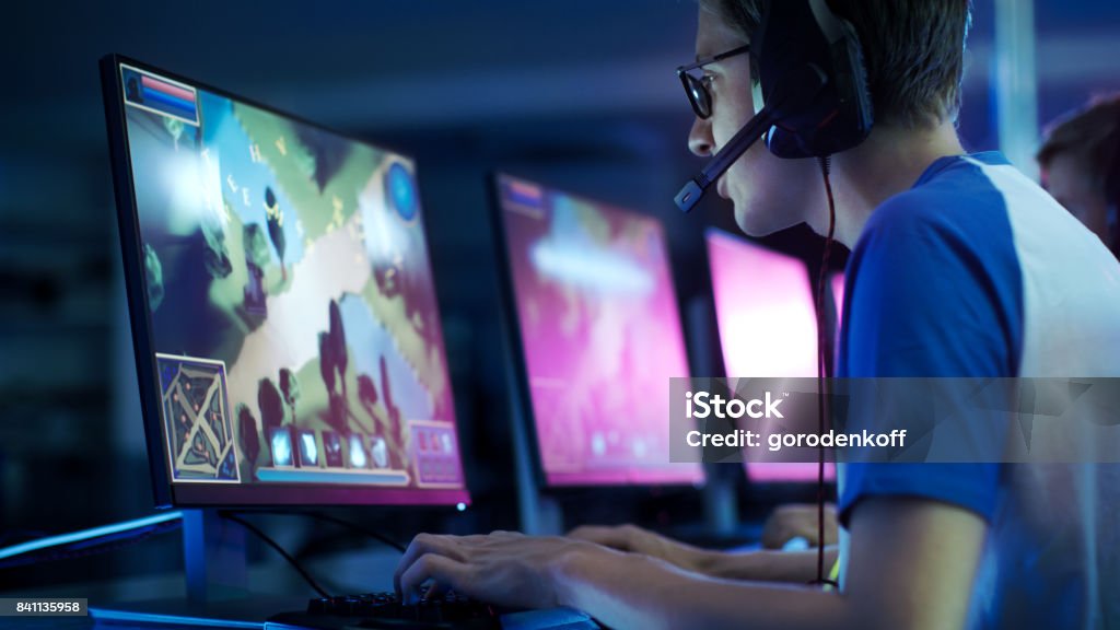 Team of Professional eSport Gamers Playing in Competitive  MMORPG/ Strategy Video Game on a Cyber Games Tournament. They Talk to Each other into Microphones. Arena Looks Cool with Neon Lights. Video Game Stock Photo