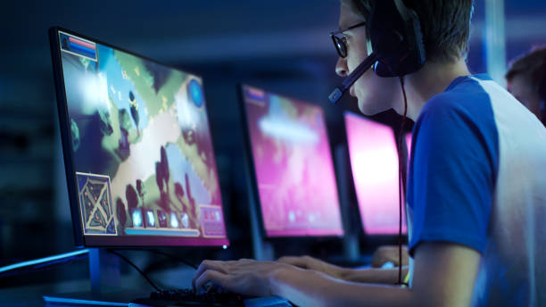 team of professional esport gamers playing in competitive  mmorpg/ strategy video game on a cyber games tournament. they talk to each other into microphones. arena looks cool with neon lights. - jogo imagens e fotografias de stock