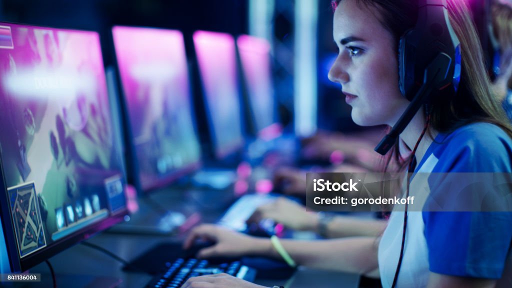 Professional Girl Gamer Plays in MMORPG/ Strategy Video Game on Her Computer. She's Participating in Online Cyber Games Tournament, Plays at Home, or in Internet Cafe. She Wears Gaming Headphones. Child Stock Photo