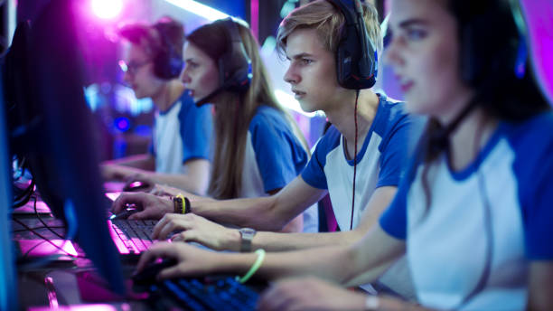 squadra di giocatori professionisti di esport che giocano in videogiochi competitivi in un torneo di videogiochi informatici. usano i microfoni. - e foto e immagini stock