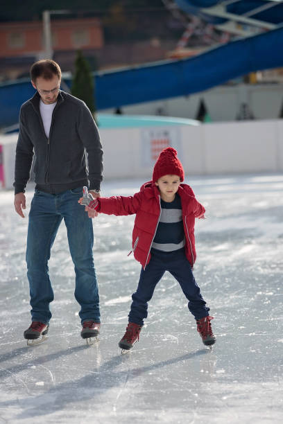 istock Happy excited little boy and his young father learning ice-skating 841148068