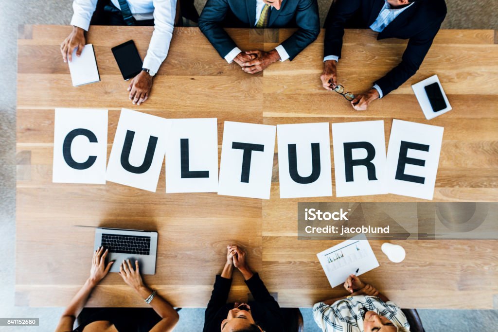 Business meeting with word Culture on table Top view of business people with word Culture on table. Business people having a meeting and discussing over work culture in office. Cultures Stock Photo