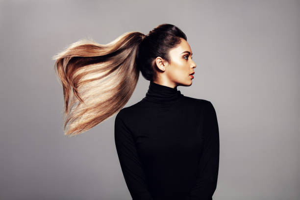 Stylish young woman with flying hair Studio shot of stylish young woman with flying hair against grey background. Female fashion model with long hair. brown hair photos stock pictures, royalty-free photos & images