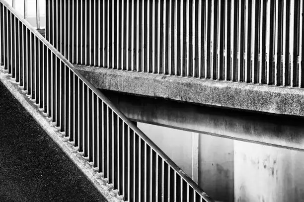 The concrete ramp leading to a pedestrian bridge over a highway makes abstract striped patterns.