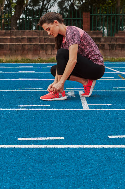 istock Female athlete tying shoe laces on running track 841171170
