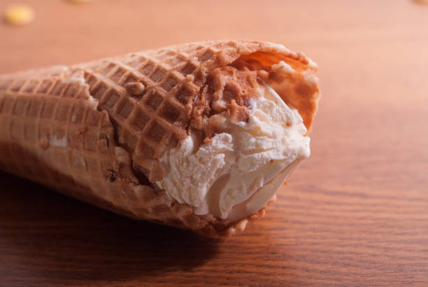 istock Vanilla ice cream in a waffle cone on a wooden table. Summer, bright sun. 841180954