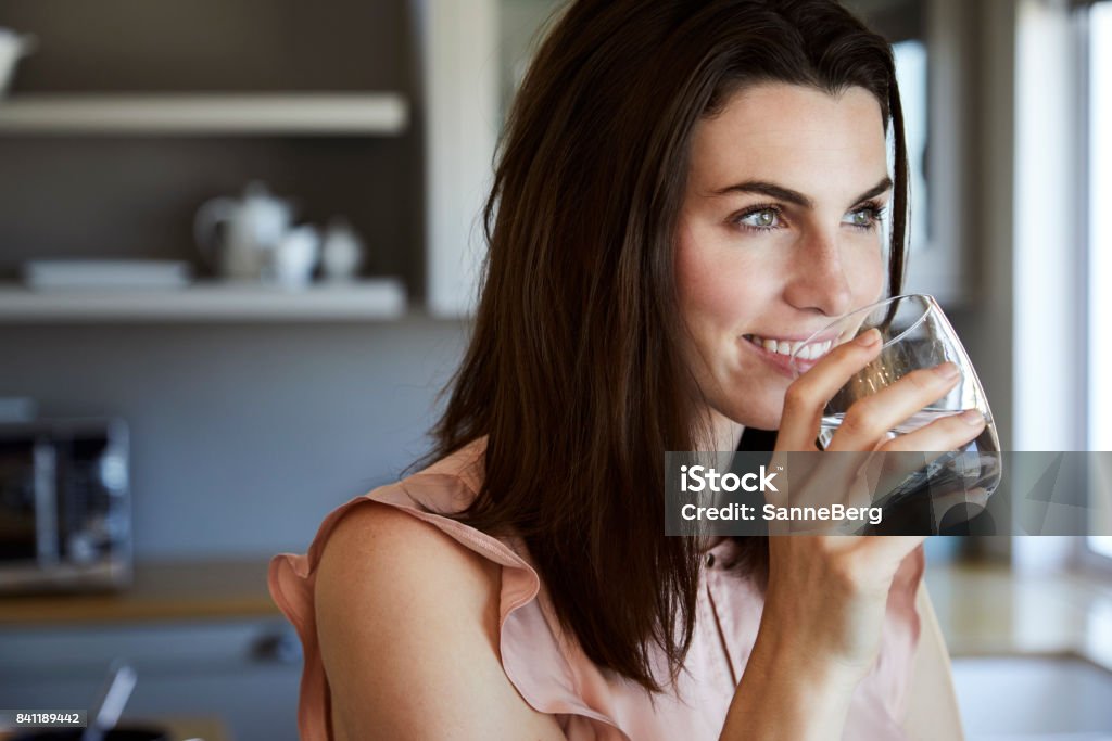 Beautiful woman in kitchen Beautiful woman drinking water and smiling in kitchen Water Stock Photo