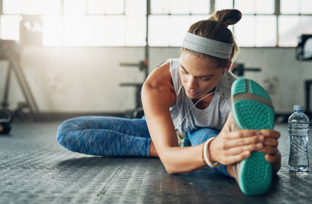 She aspires to inspire fitness in herself everyday Shot of a young attractive woman stretching in a gym cooling down photos stock pictures, royalty-free photos & images
