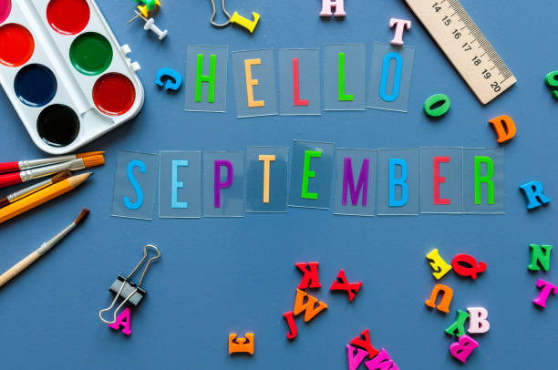 istock Hello September text on teacher or pupil table with school supplies side border on a blue background 841196510