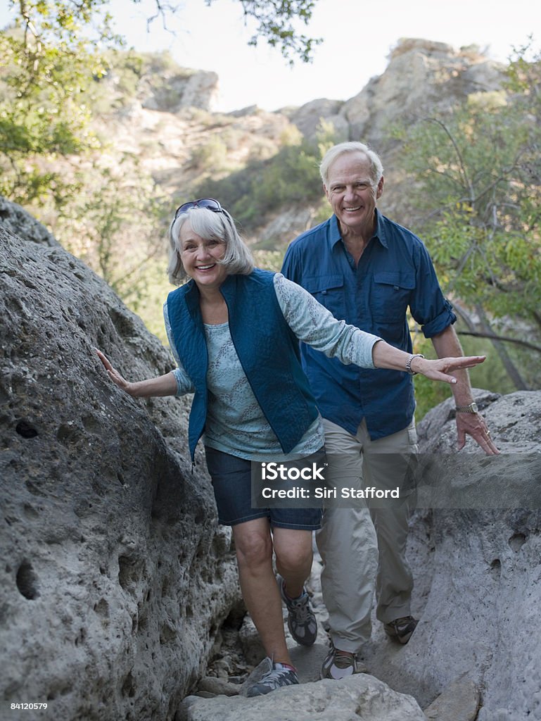 Mature couple hiking through large boulders  Hiking Stock Photo