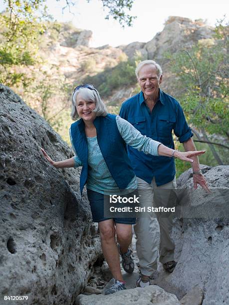 Mature Couple Hiking Through Large Boulders Stock Photo - Download Image Now - Hiking, Senior Couple, Senior Adult