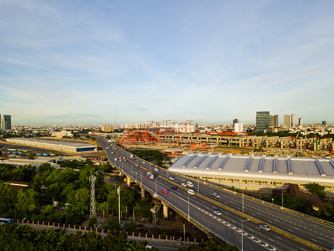 The morning call from sunrises with the aerial view of cars travel on highway and the country infrastructure of new train station in Bangkok city, Thailand.