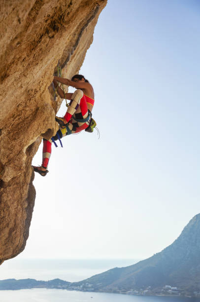 istock Young woman struggling to climb challenging route 841208550