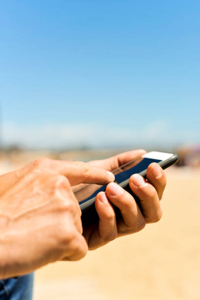 man using a smartphone next to the beach - sexting imagens e fotografias de stock
