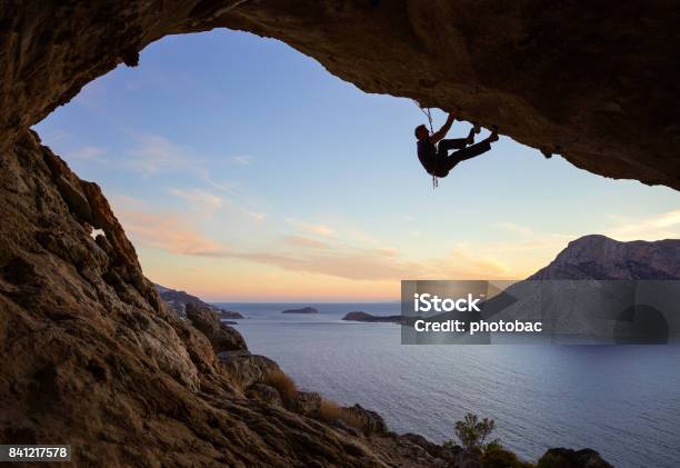 Giovane Che Si Arrampica Lungo Il Soffitto Della Grotta Al Tramonto - Fotografie stock e altre immagini di Arrampicata su roccia