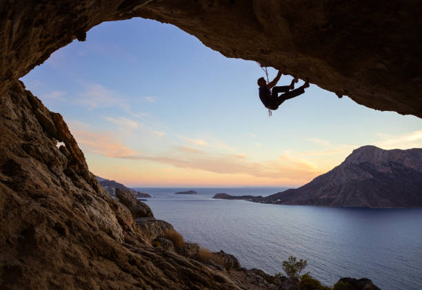 istock Young man climbing along ceiling of cave at sunset 841217578