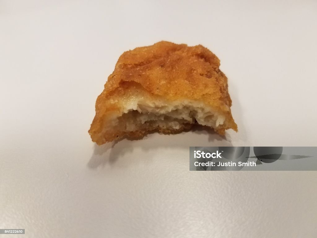 a chicken nugget with a bite taken out of it a delicious chicken nugget with a bite taken out of it Biting Stock Photo