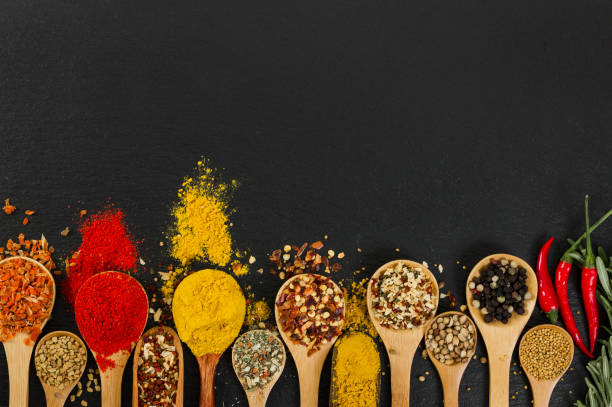 istock Various spices in wooden spoons on black slate background. 841226216