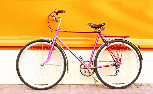 istock Retro old pink bicycle stands on a colorful orange background 841229236