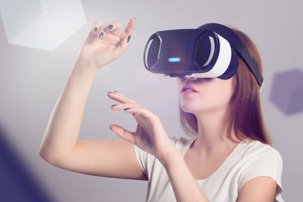 istock Woman in VR headset looking up and trying to touch objects in virtual reality 841230712