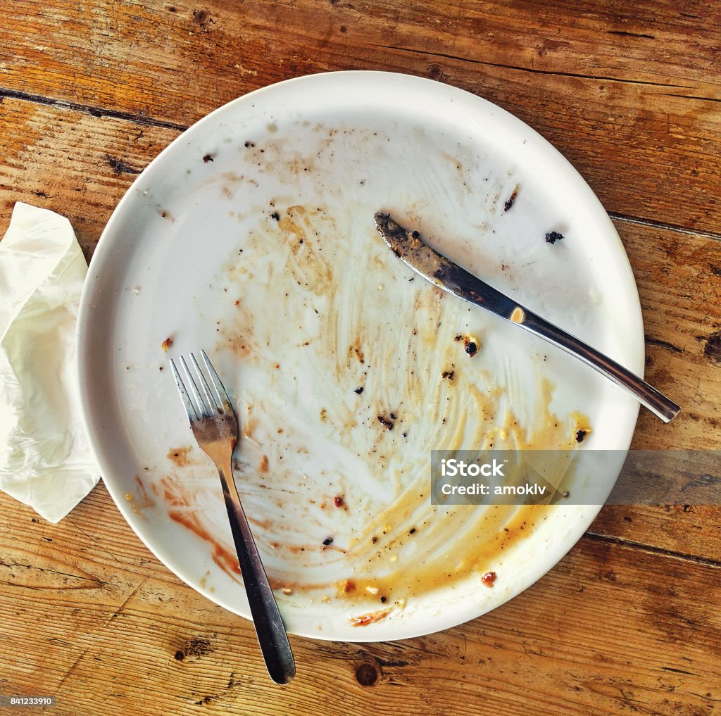 Plate Empty dirty plate with fork and knife on the wooden table and crumpled napkin Plate Stock Photo